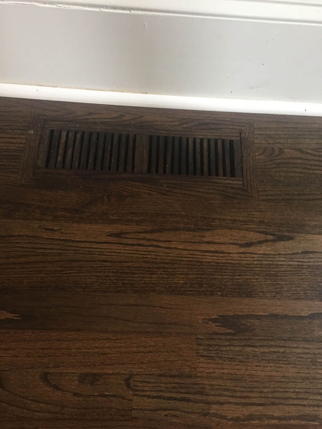 A close up of a wooden floor with a vent on it.