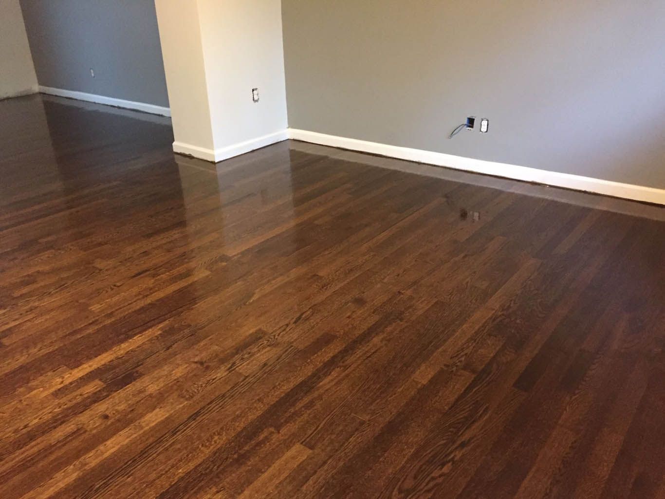 A living room with hardwood floors and a gray wall.