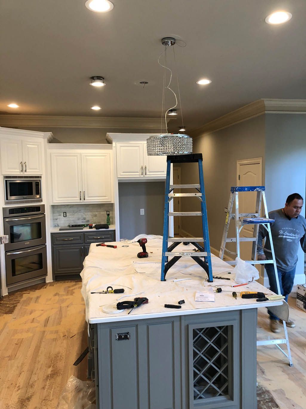 A man is standing on a ladder in a kitchen.
