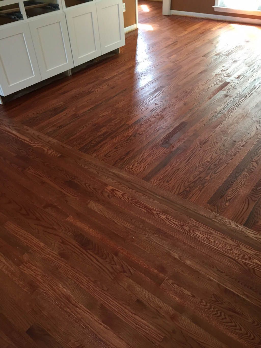 A living room with hardwood floors and white cabinets.
