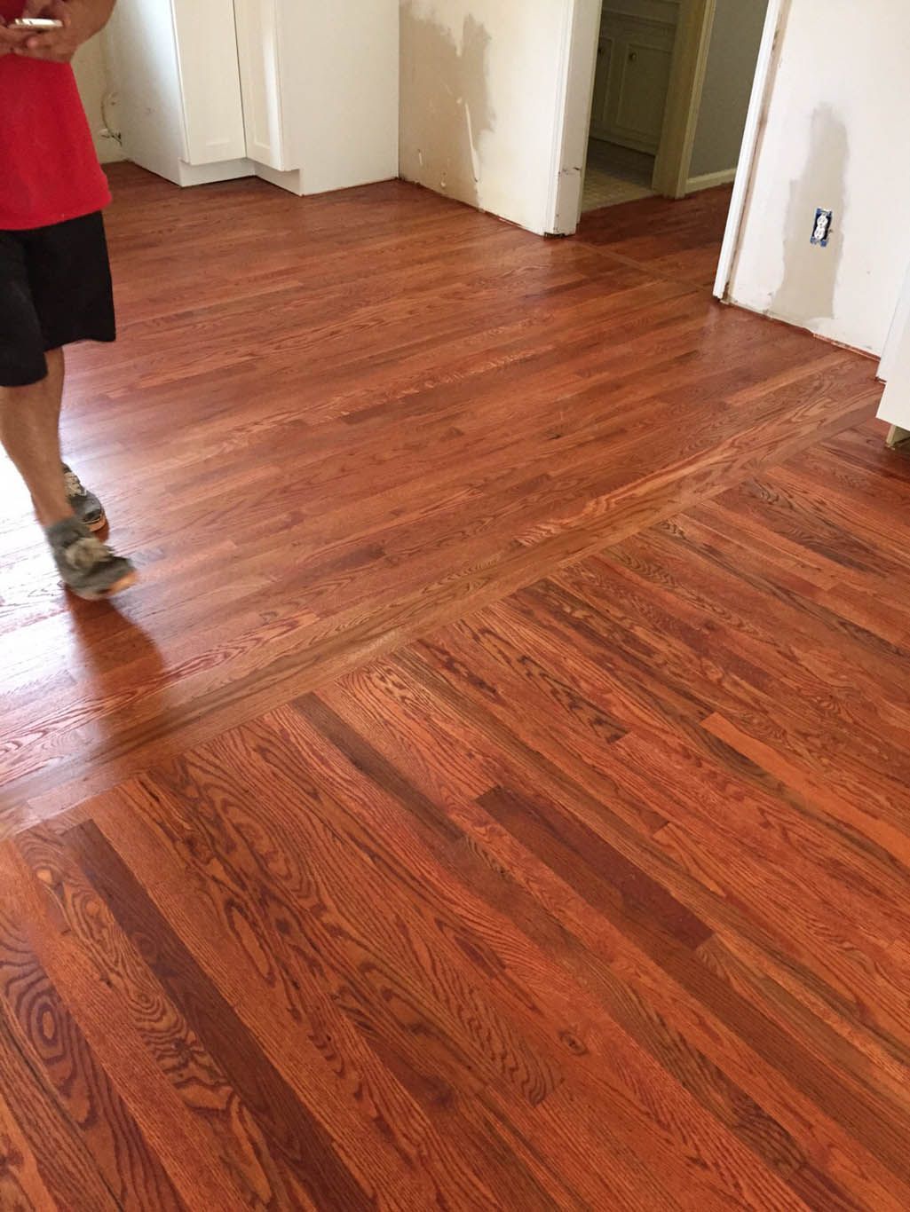 A person is standing on a wooden floor in a room.