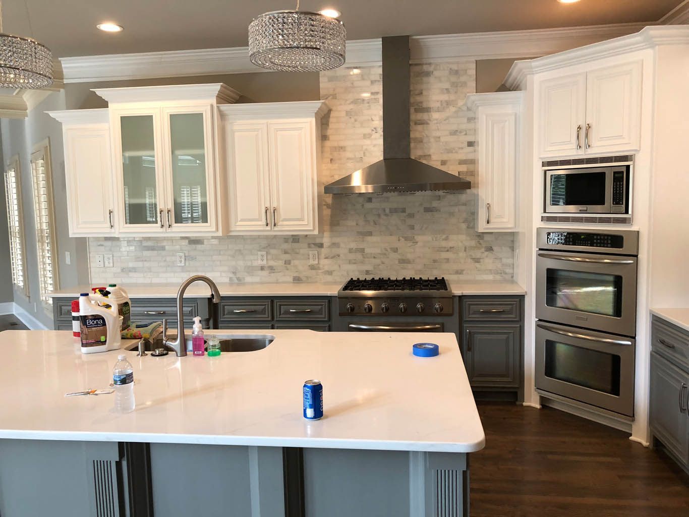 A kitchen with white cabinets , stainless steel appliances and a large island.