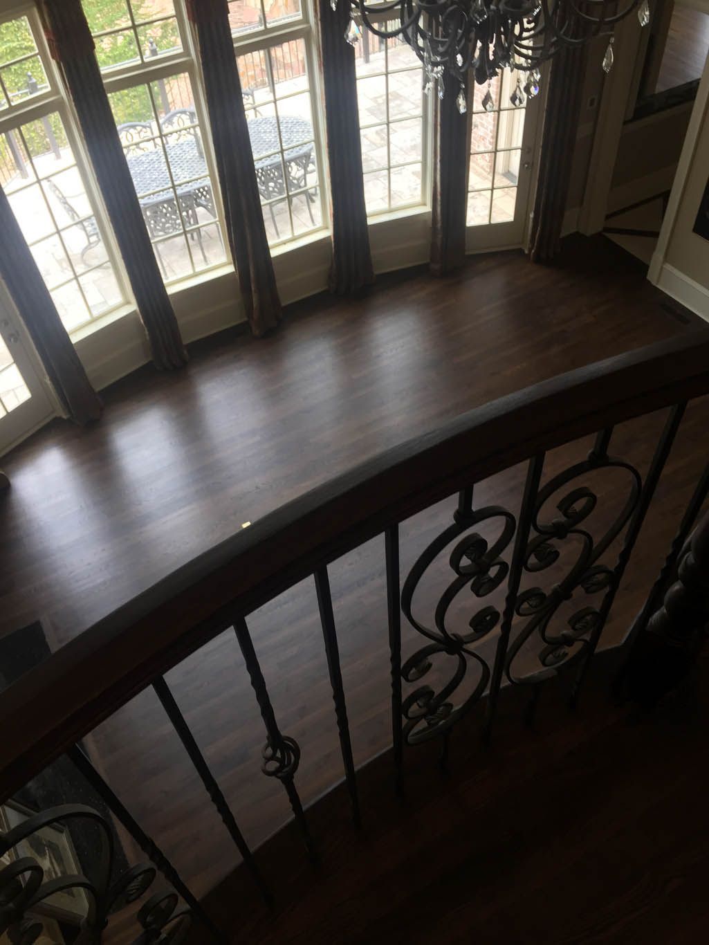An aerial view of a wooden staircase with a wrought iron railing.