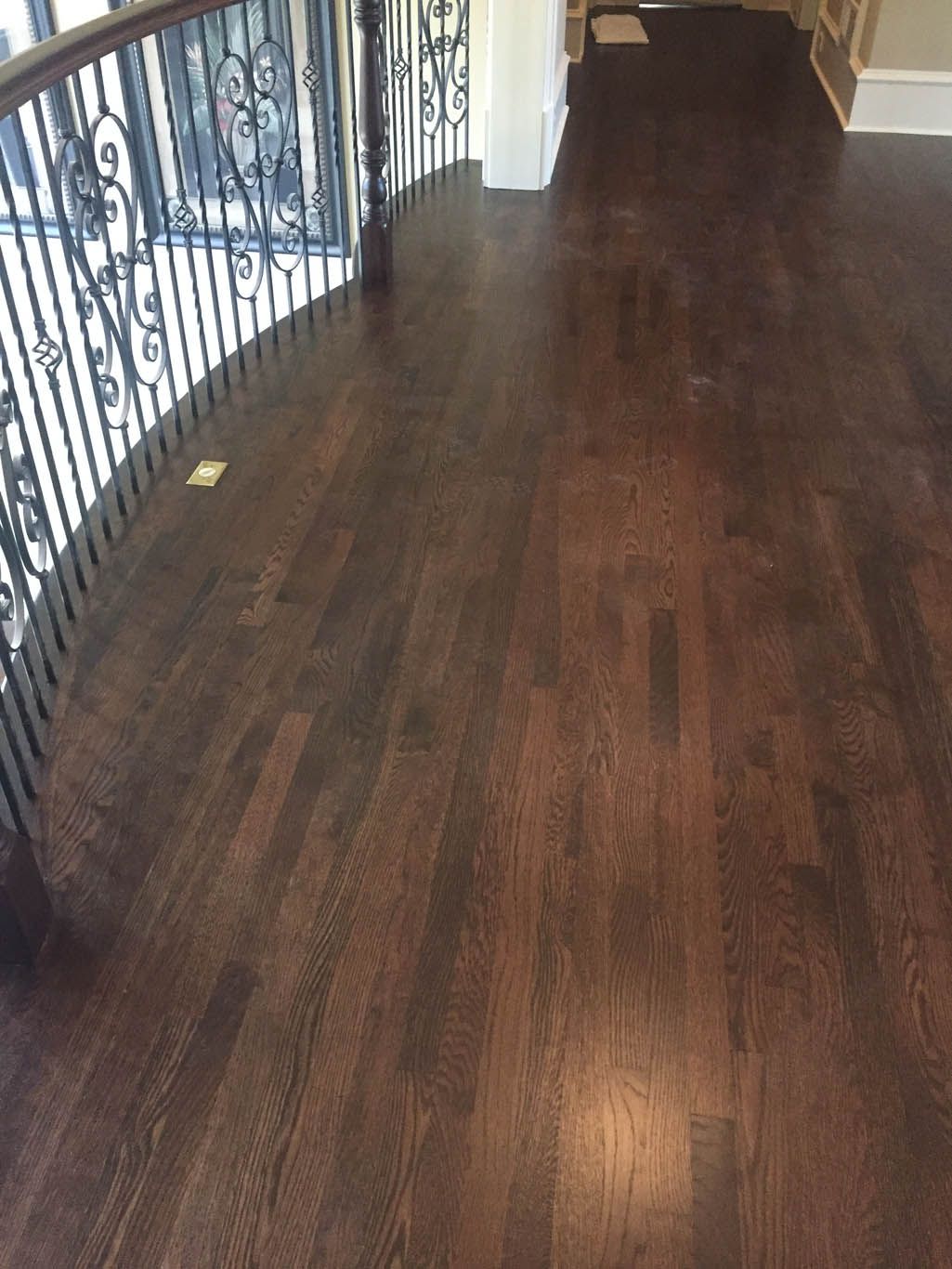 A dark wooden floor with a wrought iron railing in a living room.