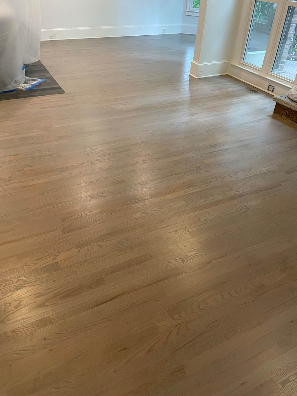 A wooden floor in a living room with a window.