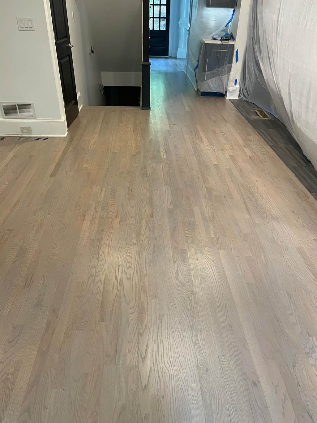 A wooden floor in a room with a staircase in the background.