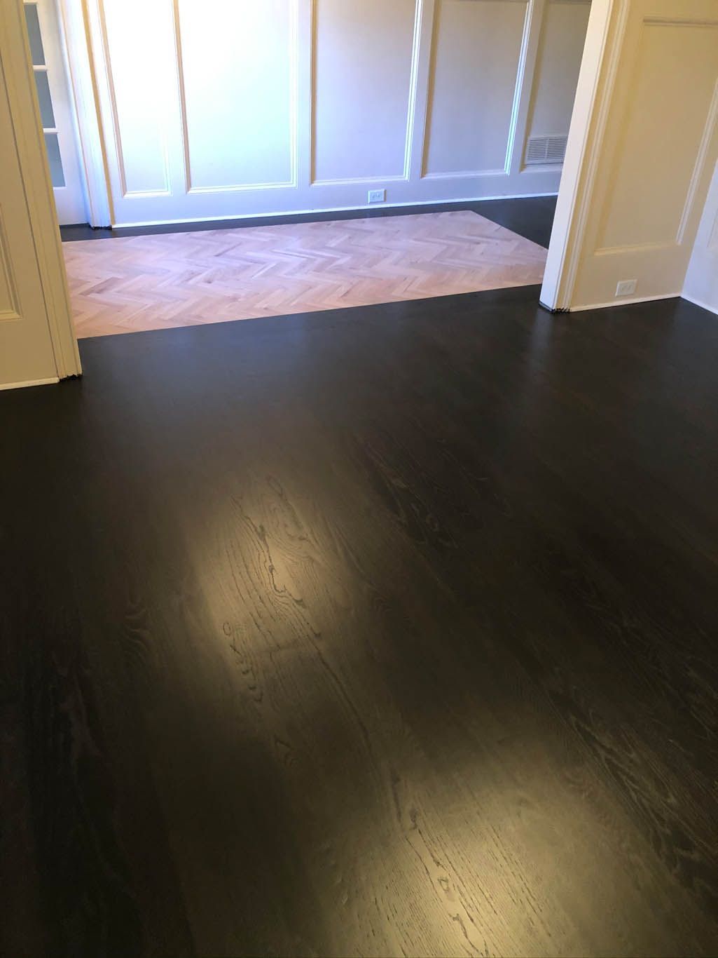 A room with a black wooden floor and white walls.