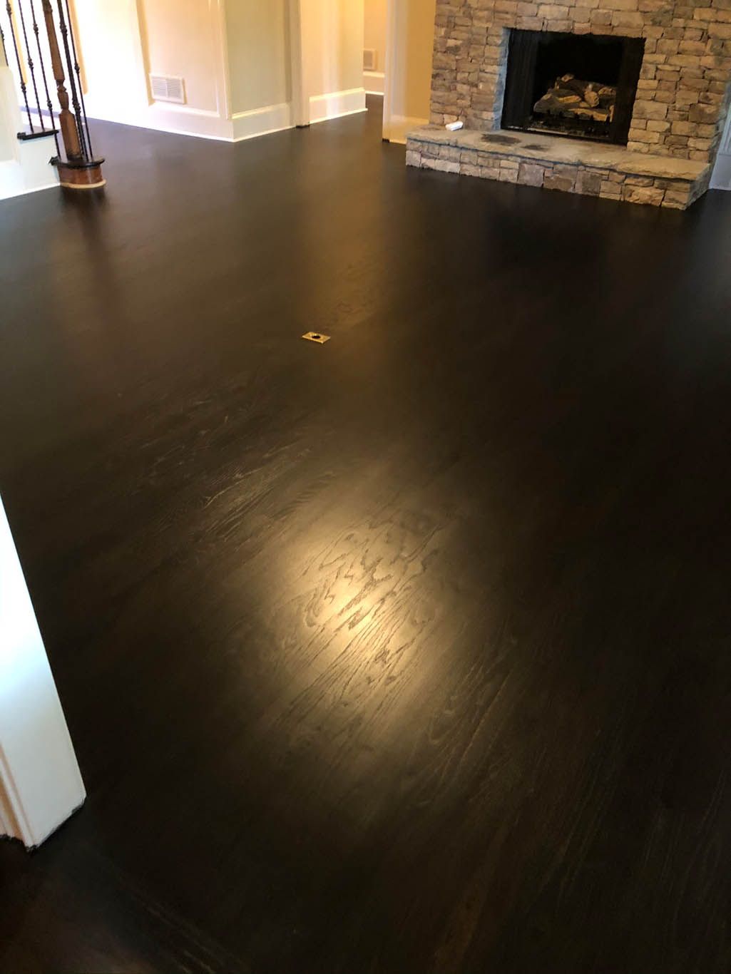 A living room with a dark wooden floor and a fireplace.