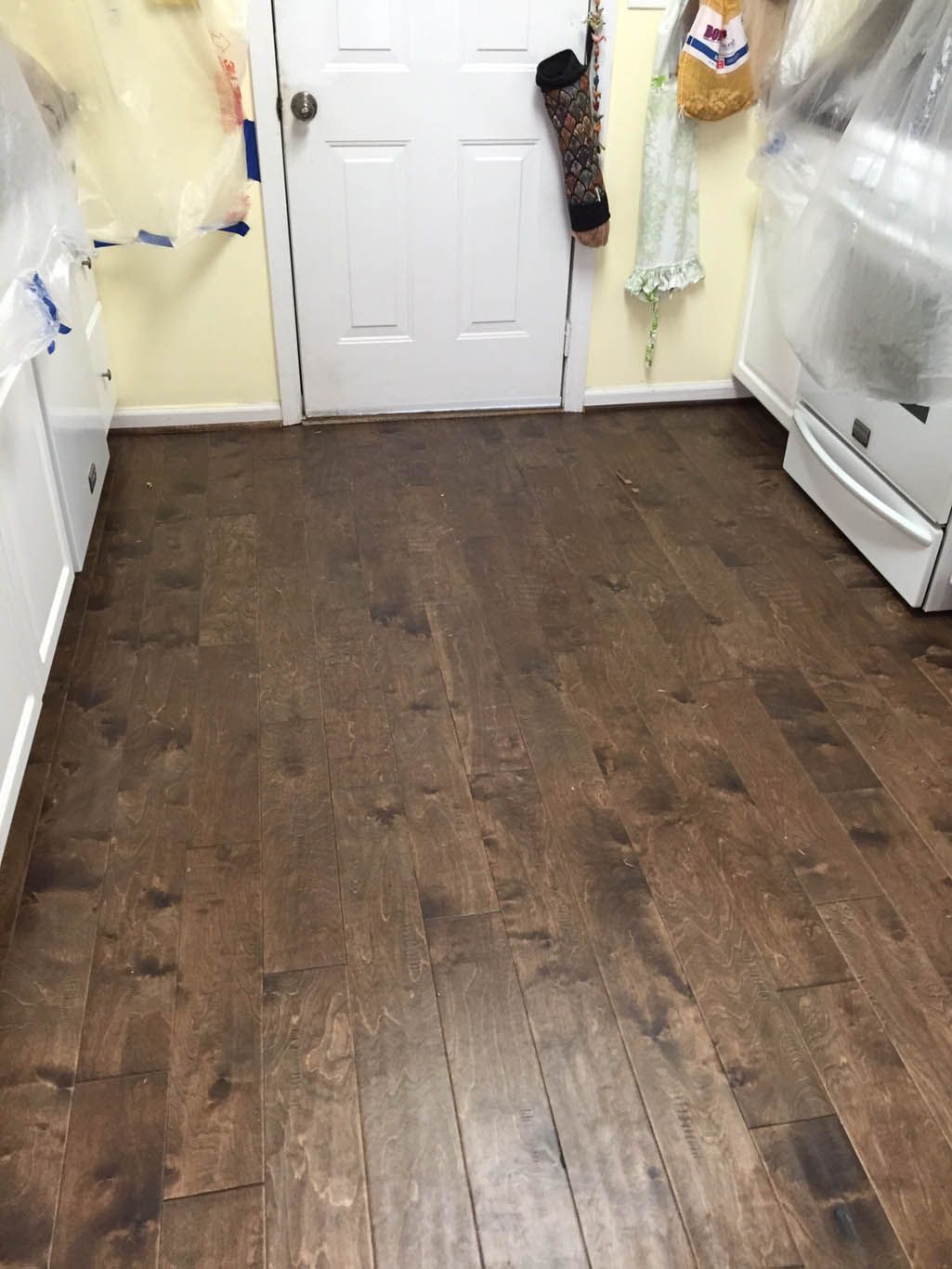 A kitchen with a wooden floor and a white refrigerator.