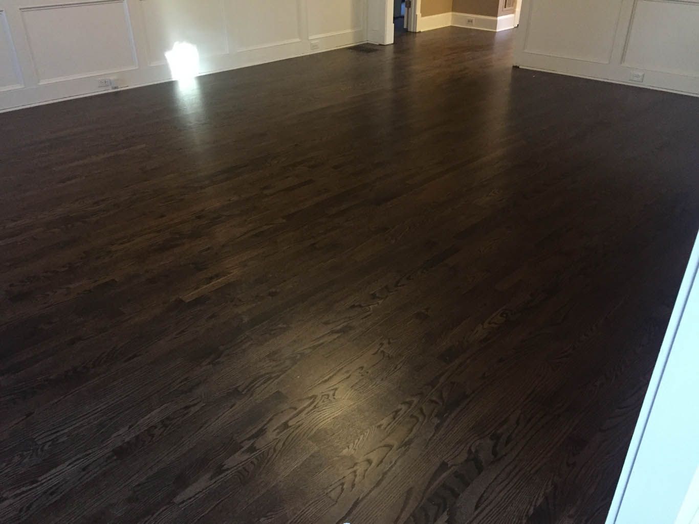 A room with a dark wooden floor and white walls