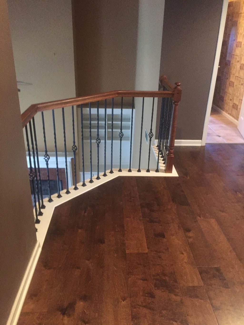 A wooden staircase with a wrought iron railing in a house.