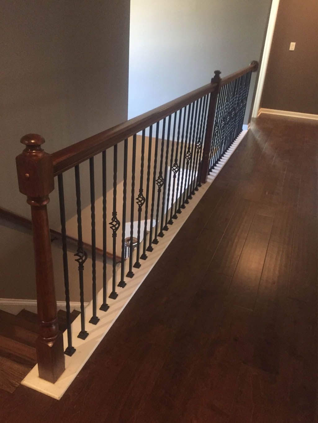 A wooden staircase with a wrought iron railing