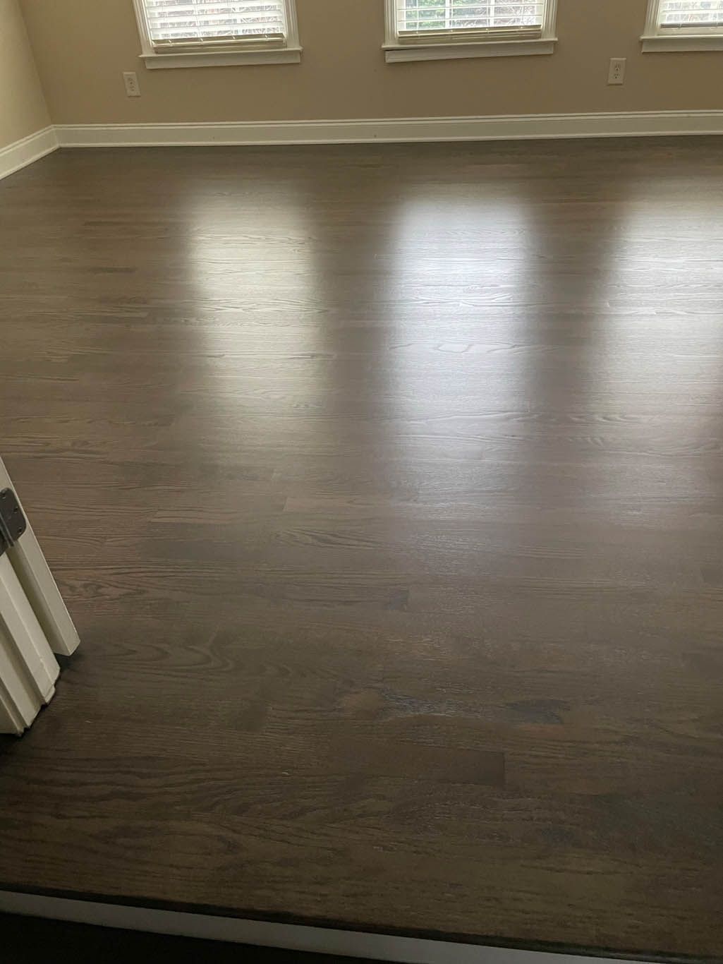 A large empty room with a wooden floor and windows.