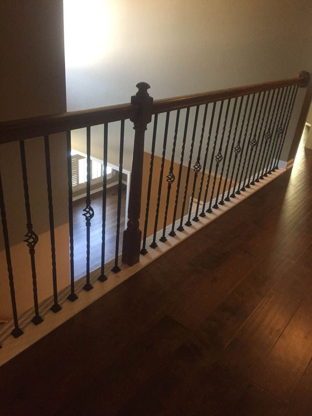 A staircase with a wrought iron railing and a wooden handrail