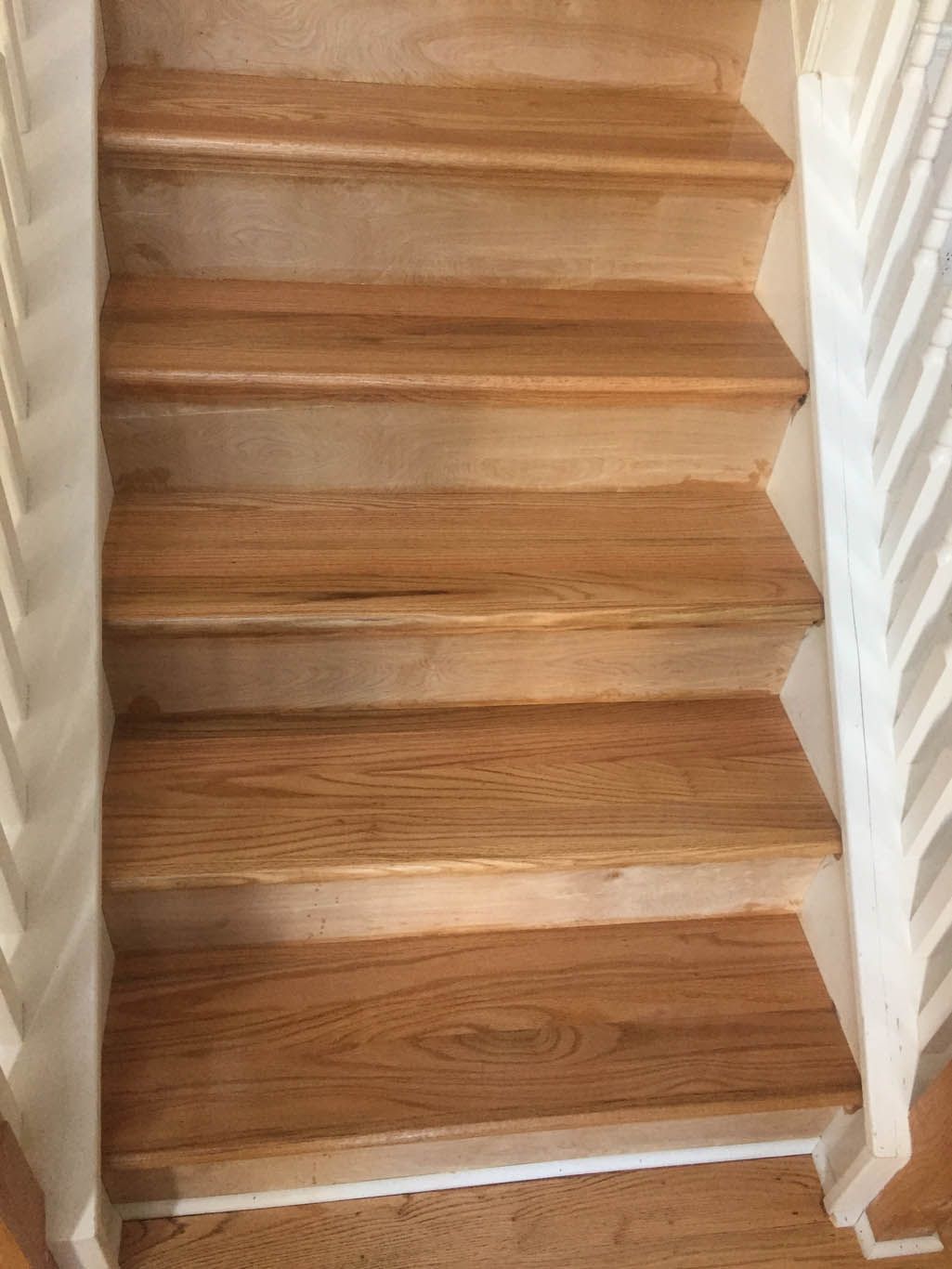 A close up of a wooden staircase with a white railing.