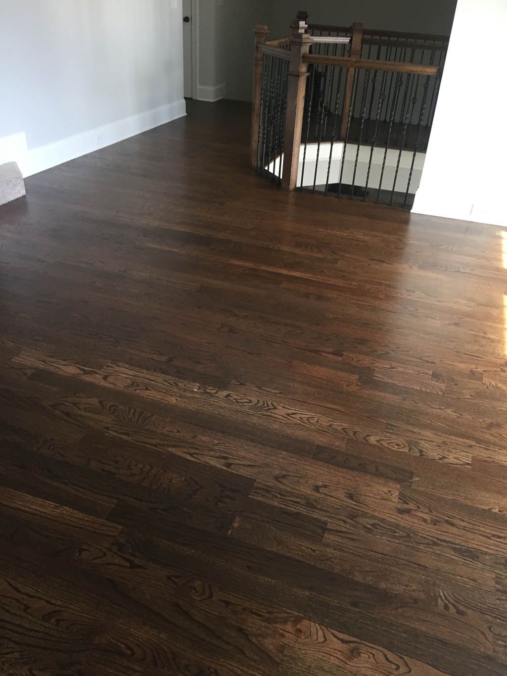 A wooden floor in a room with a staircase in the background.
