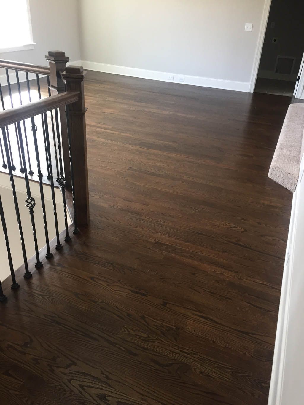 There is a staircase with a wooden floor and a wrought iron railing.