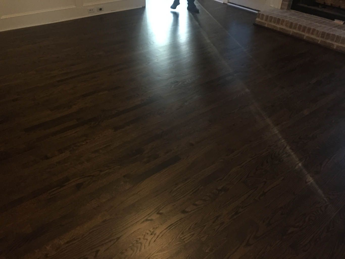 A person is walking on a wooden floor in a living room