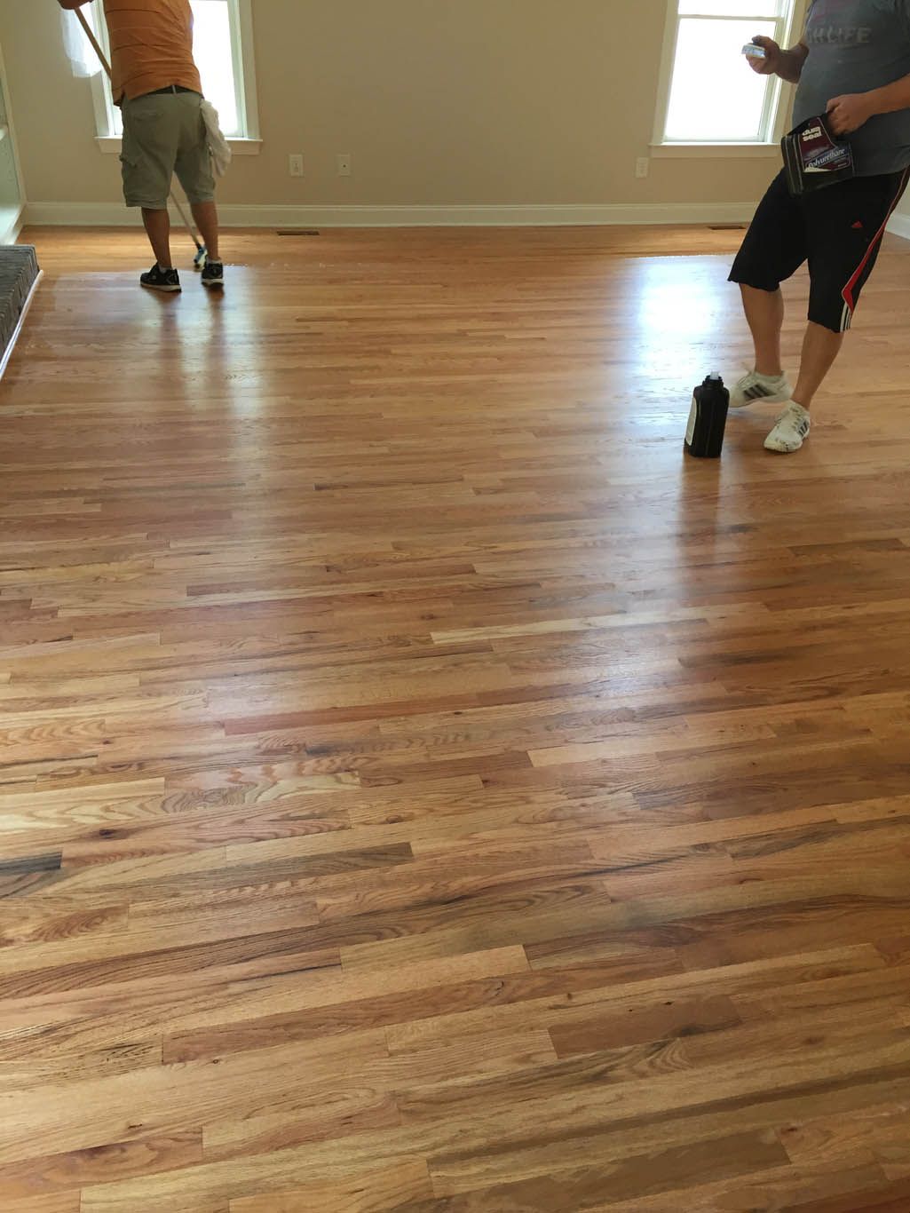 Two men are standing on a wooden floor in a room.