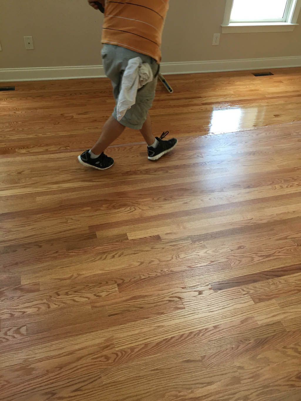 A person is walking on a wooden floor in a room.