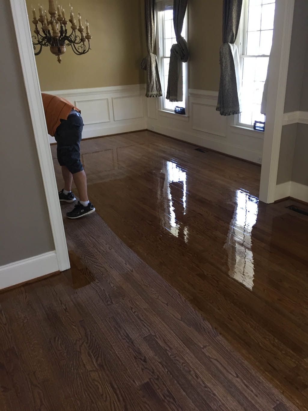 A man is kneeling on a wooden floor in a living room.