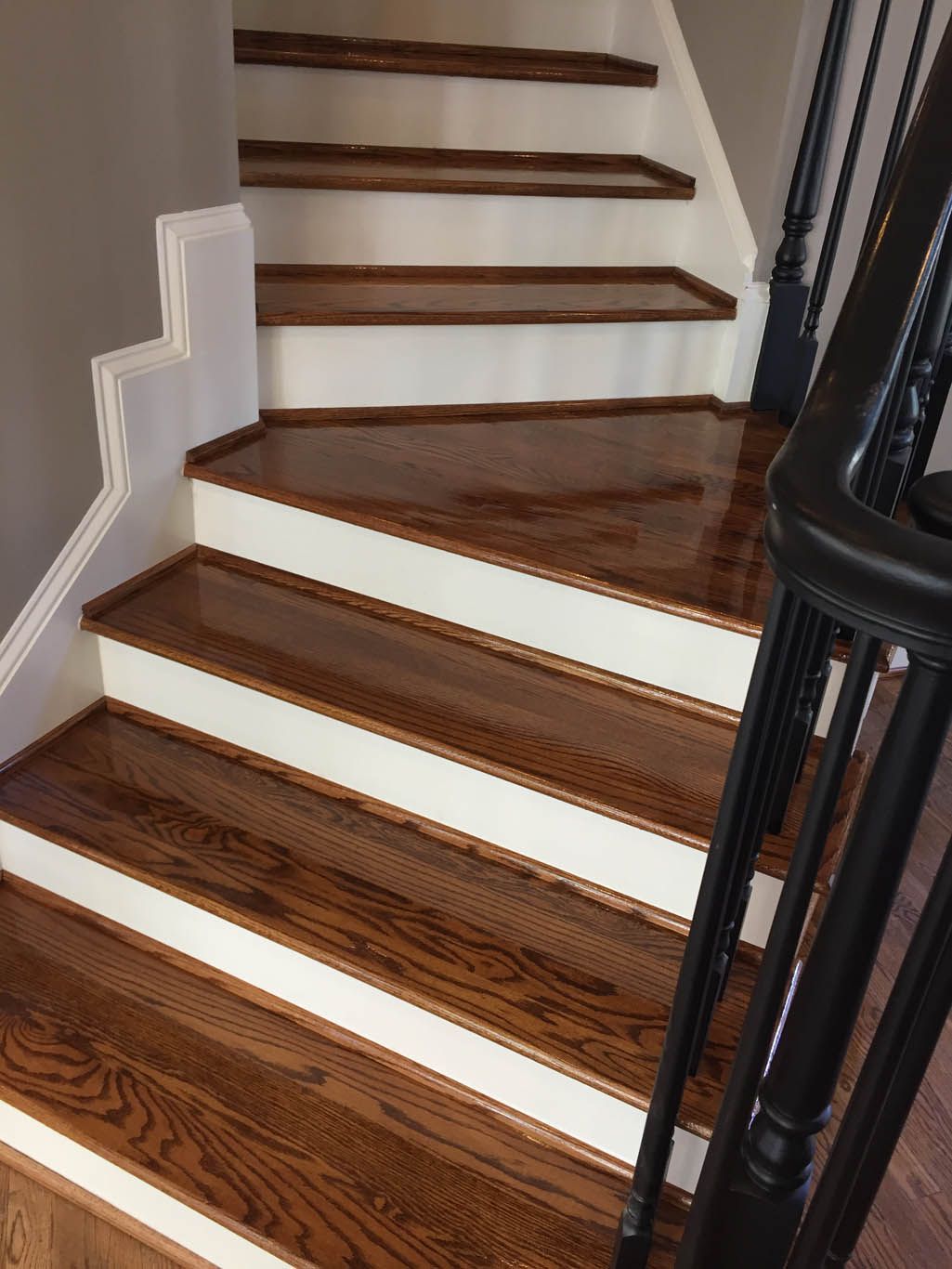 A wooden staircase with white steps and a black railing.