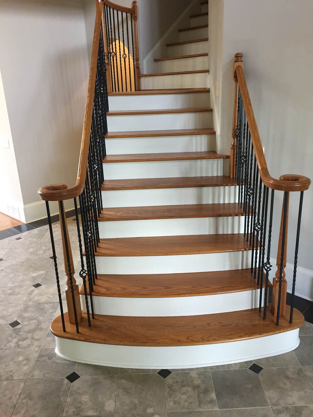 A wooden staircase with white steps and a wrought iron railing.