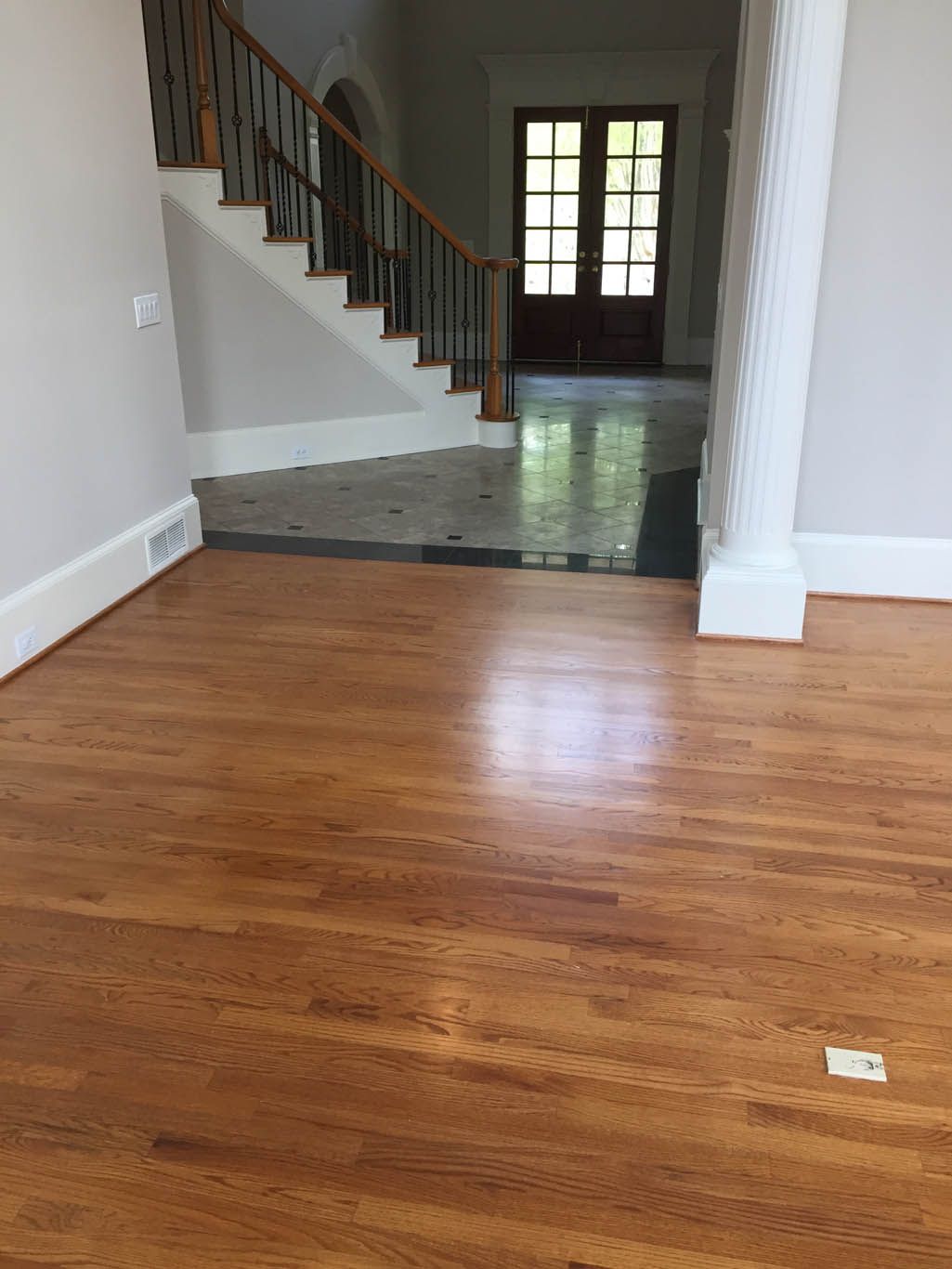 A living room with hardwood floors and stairs in a house.