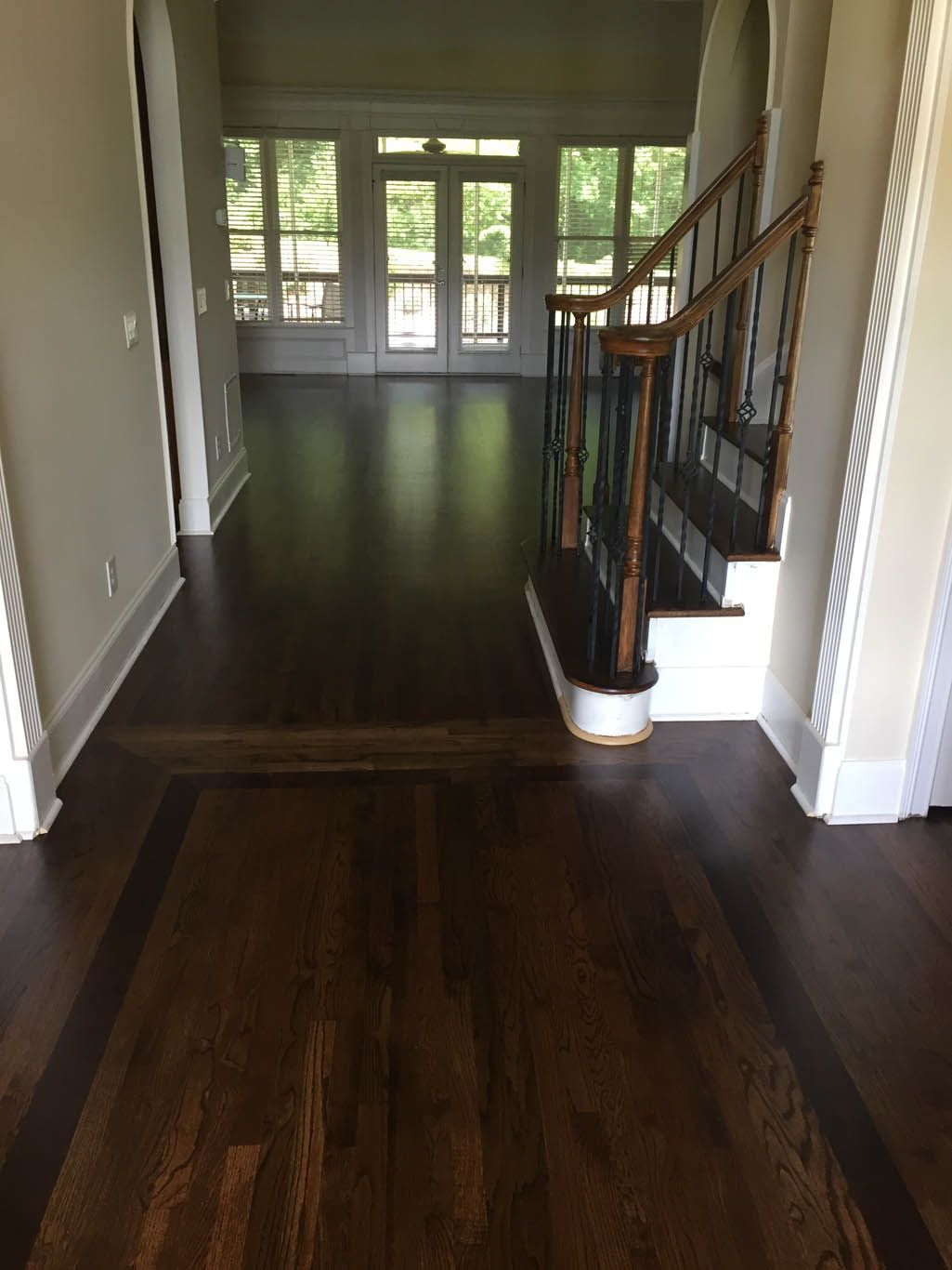 A hallway with a wooden floor and stairs in a house.