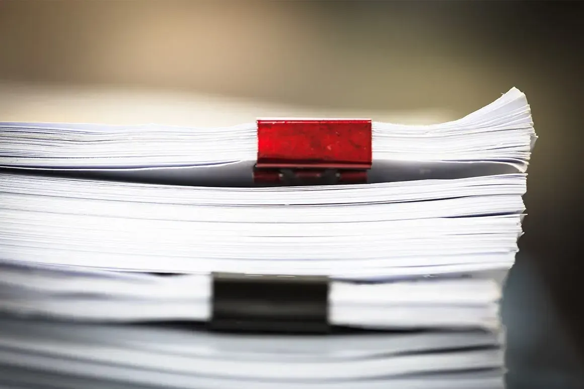 A Stack Of Paper With A Red Clip On Top Of It — McNeilly Lawyers In Kempsey, NSW