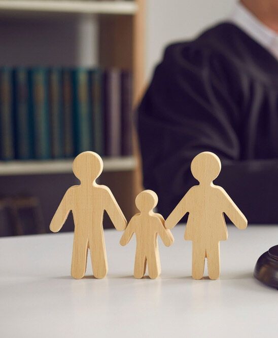 Three Wooden Figures Of A Family Are Sitting On A Table In Front Of A Judge — McNeilly Lawyers In Kempsey, NSW