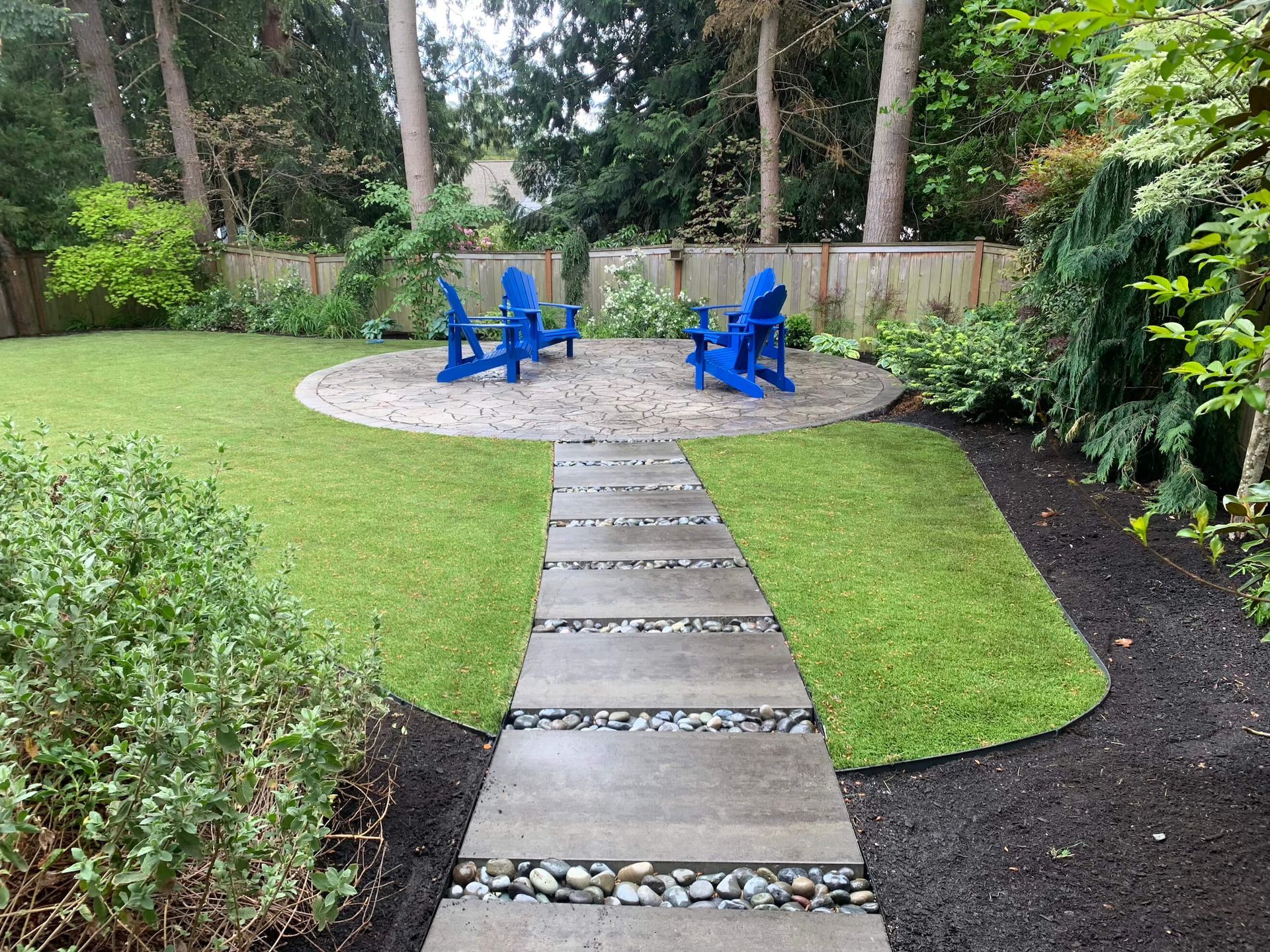 Two blue lawn chairs are sitting in the middle of a lush green yard.