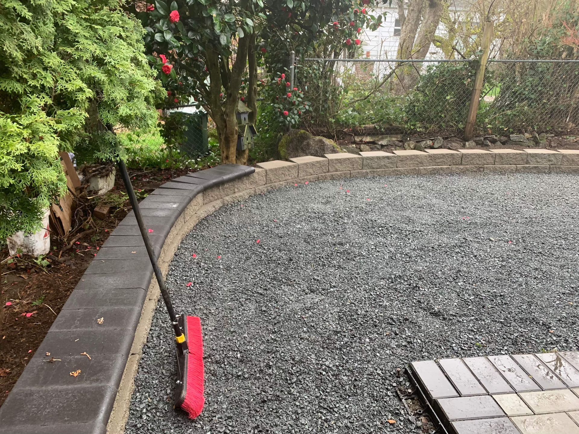 A red broom is sitting on top of a pile of gravel.