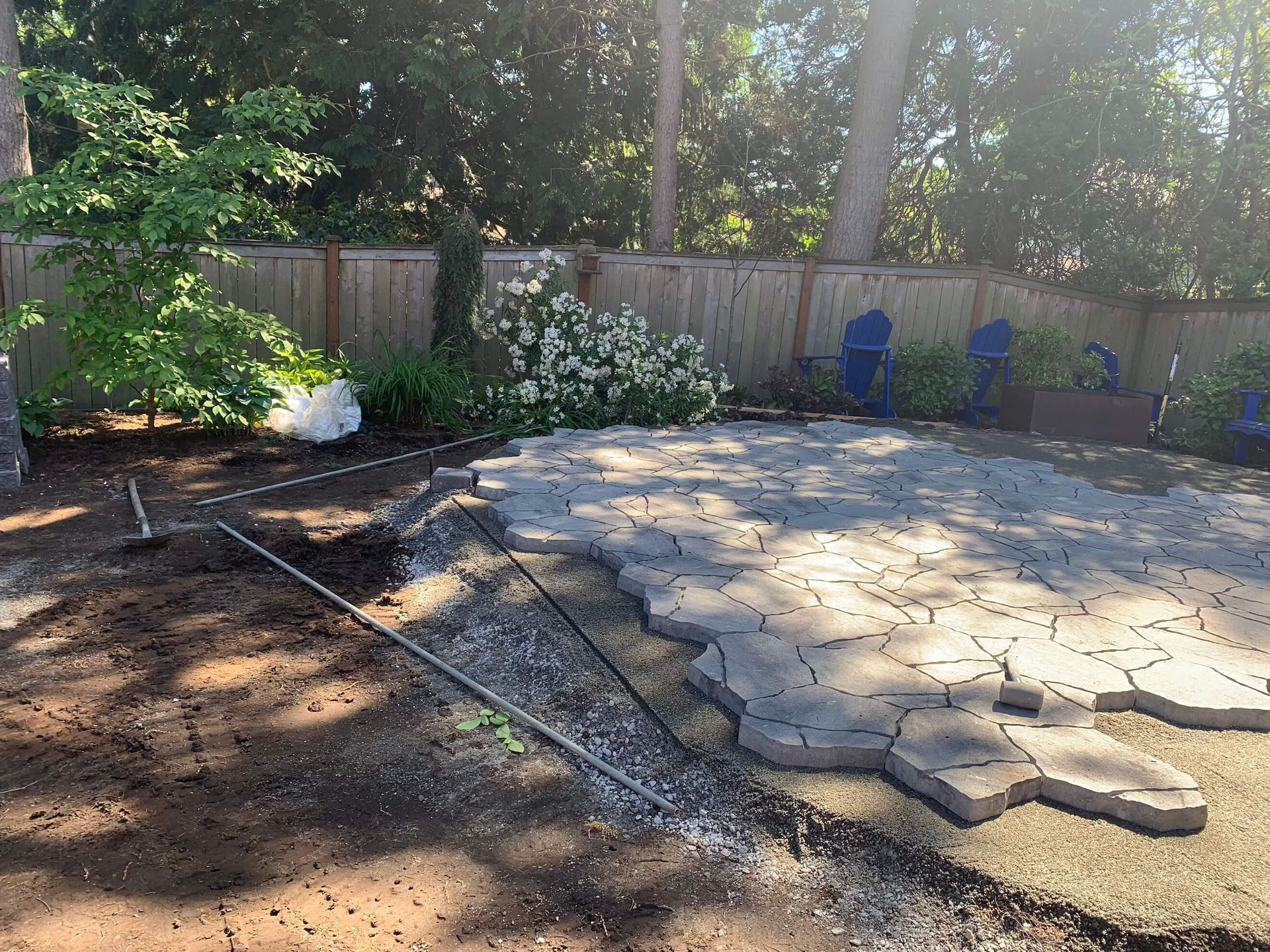 A patio is being built in a backyard with a fence in the background.