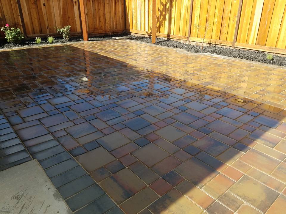 A brick patio with a wooden fence in the background.
