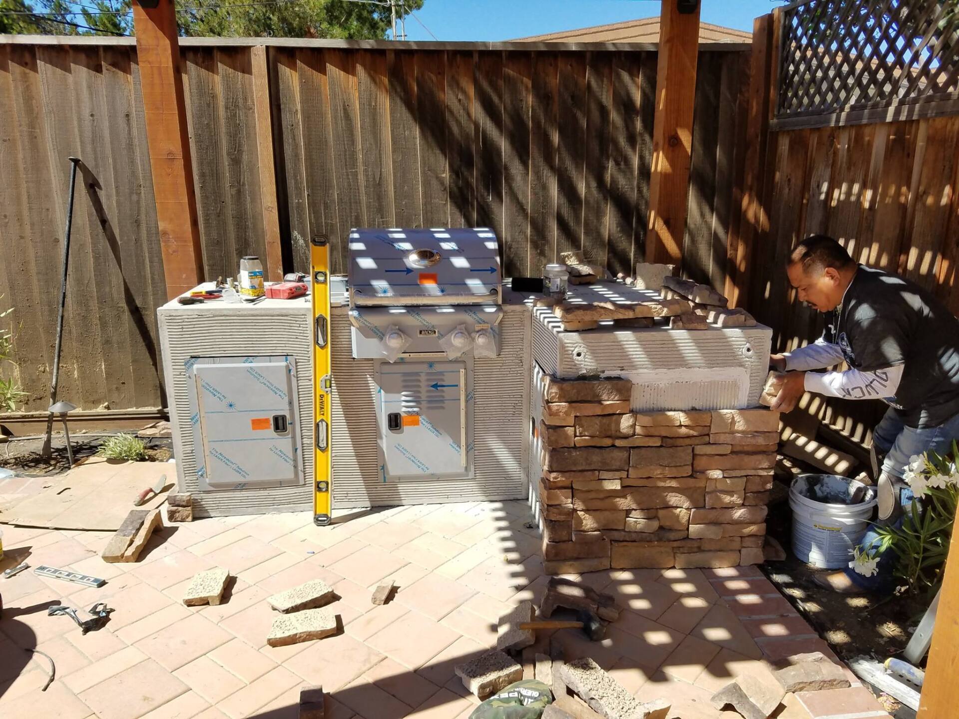 A man is working on a grill in a backyard.