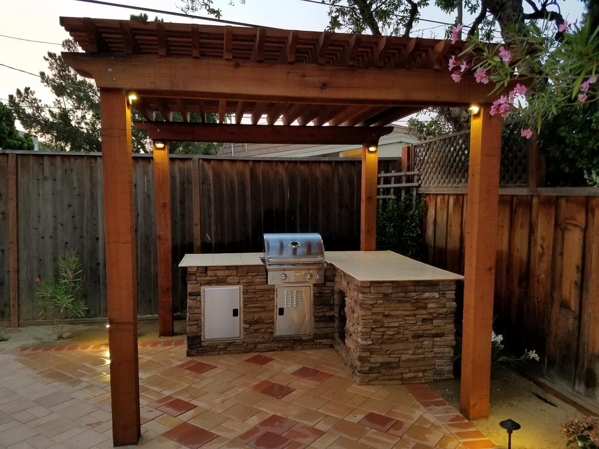 A wooden pergola with a grill underneath it