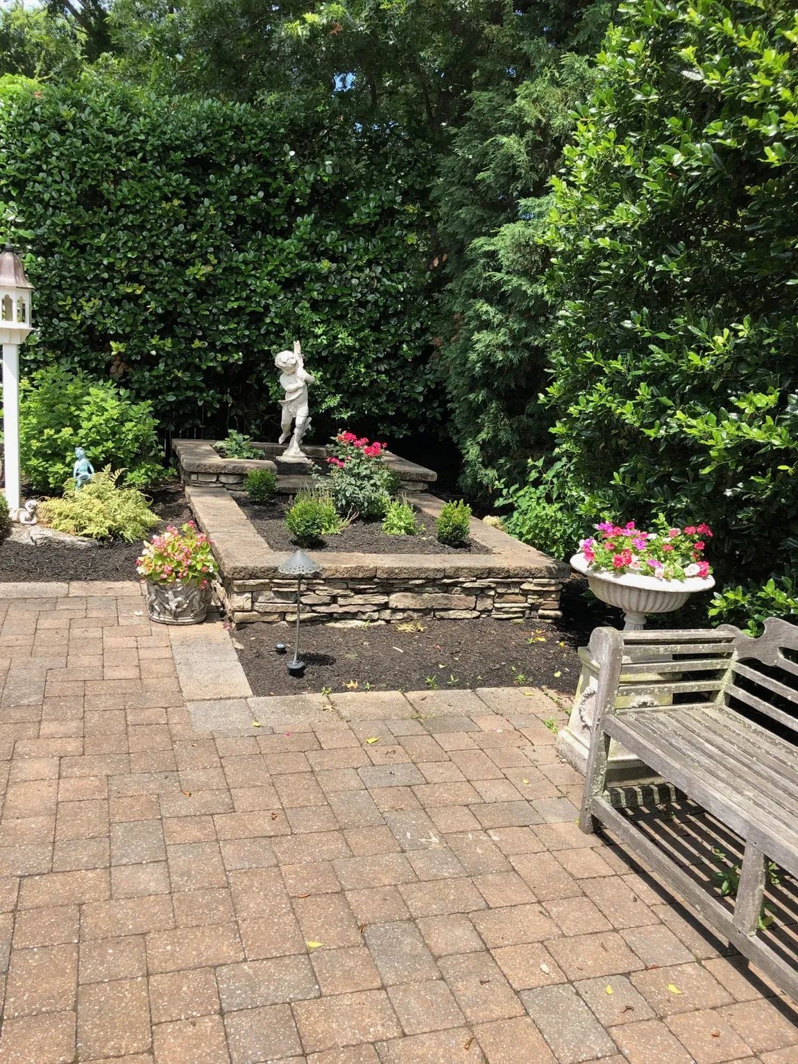 A patio with a bench and a statue in the middle of it.