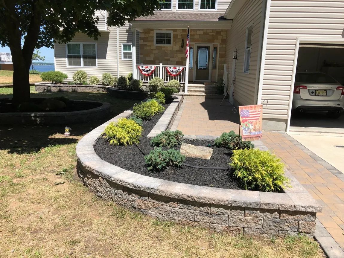 A house with a car parked in the garage and a planter in front of it.