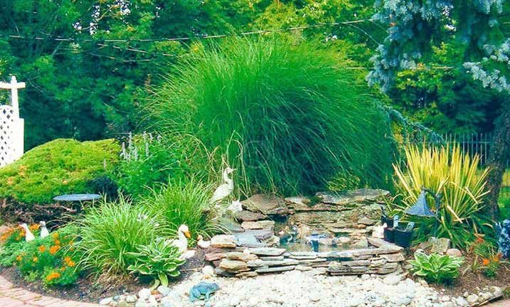 A garden with a waterfall and a cross in the background