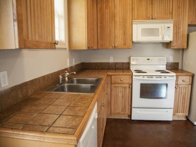 Kitchen with tile counters and white appliances