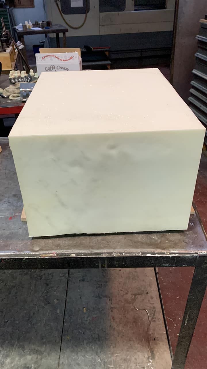 Un grande blocco rettangolare di schiuma chiara è appoggiato su un tavolo di metallo.