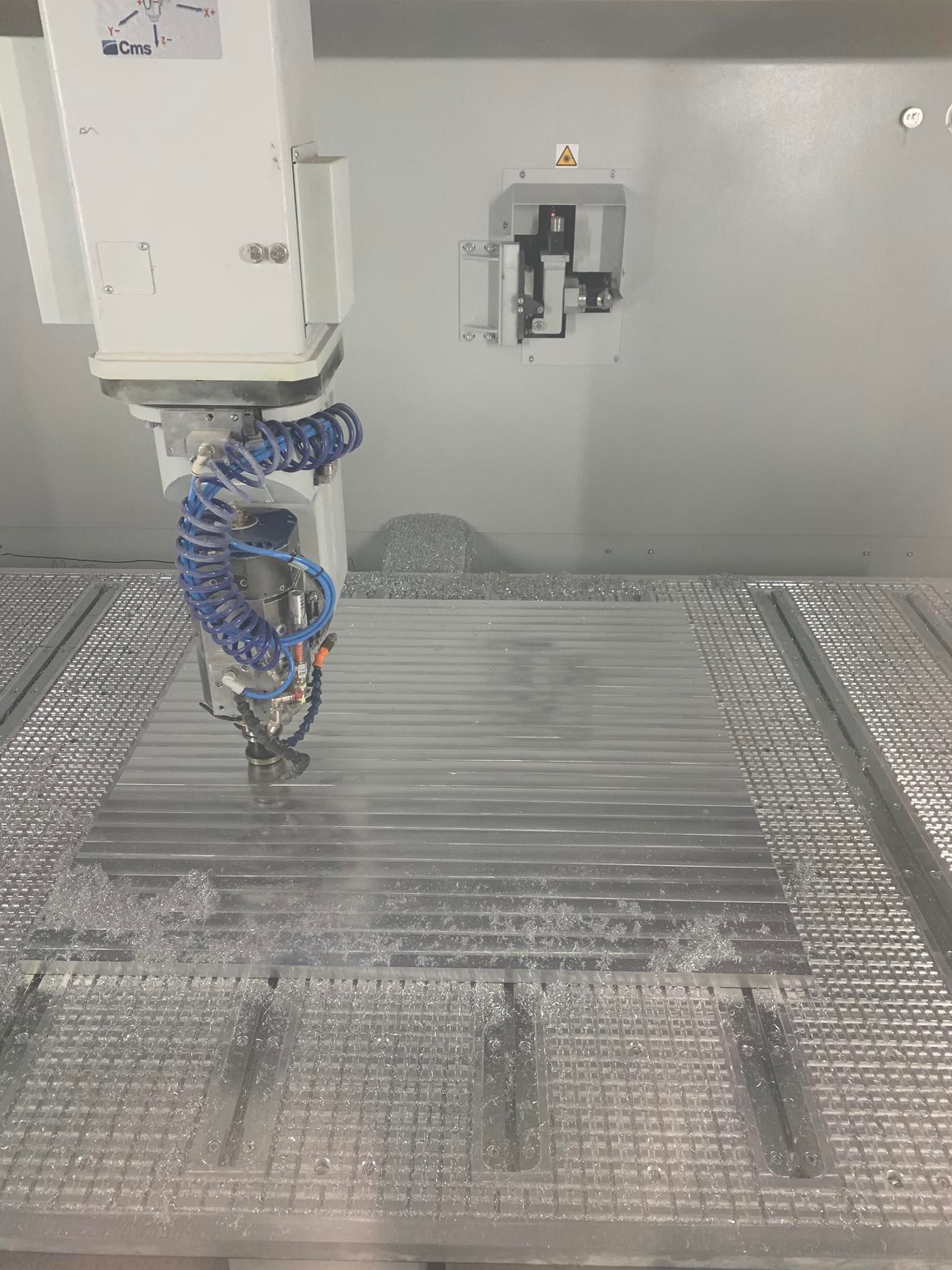 Fresatrice CNC che taglia il metallo, creando scanalature parallele, con trucioli di metallo sul letto.