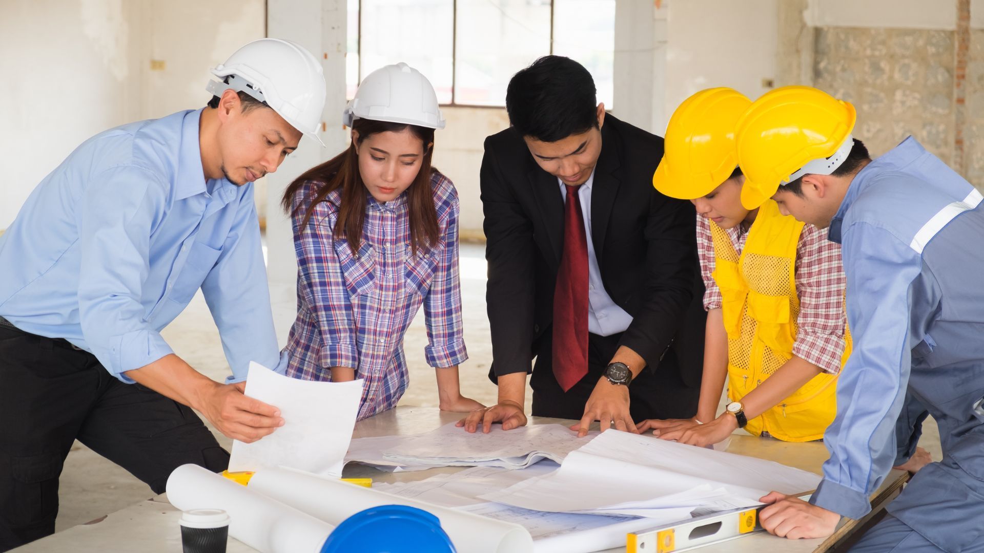 A group of construction workers are looking at a blueprint.