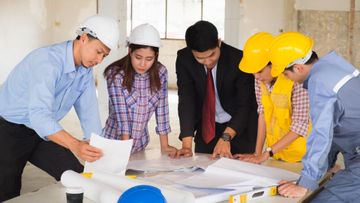 A group of construction workers are looking at a blueprint.