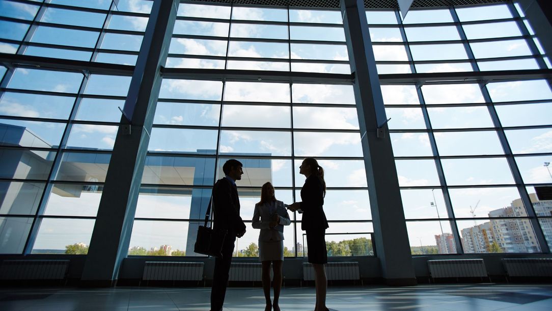 A group of people are standing in front of a large window.