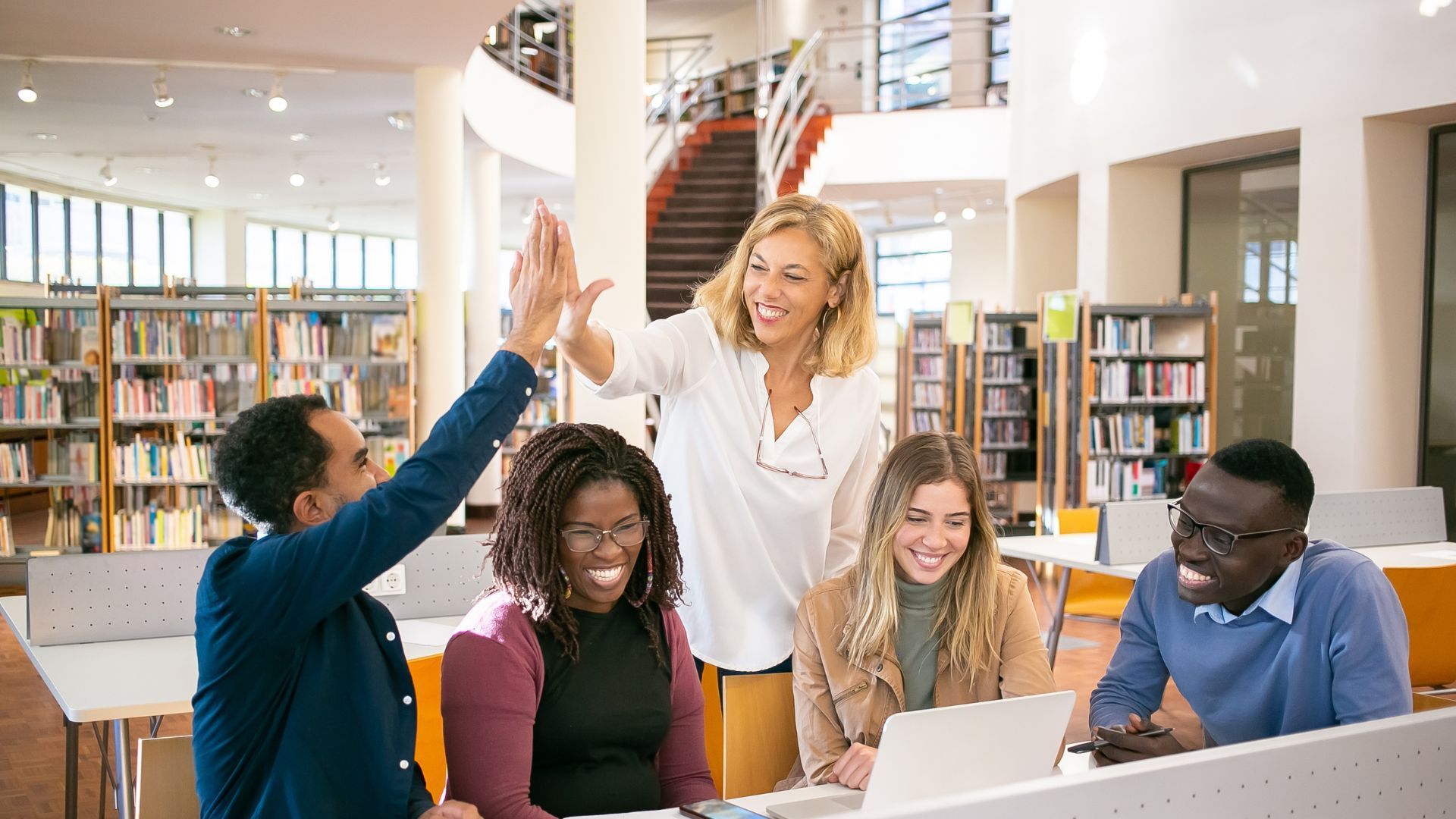 A group of people are giving each other a high five in a library.