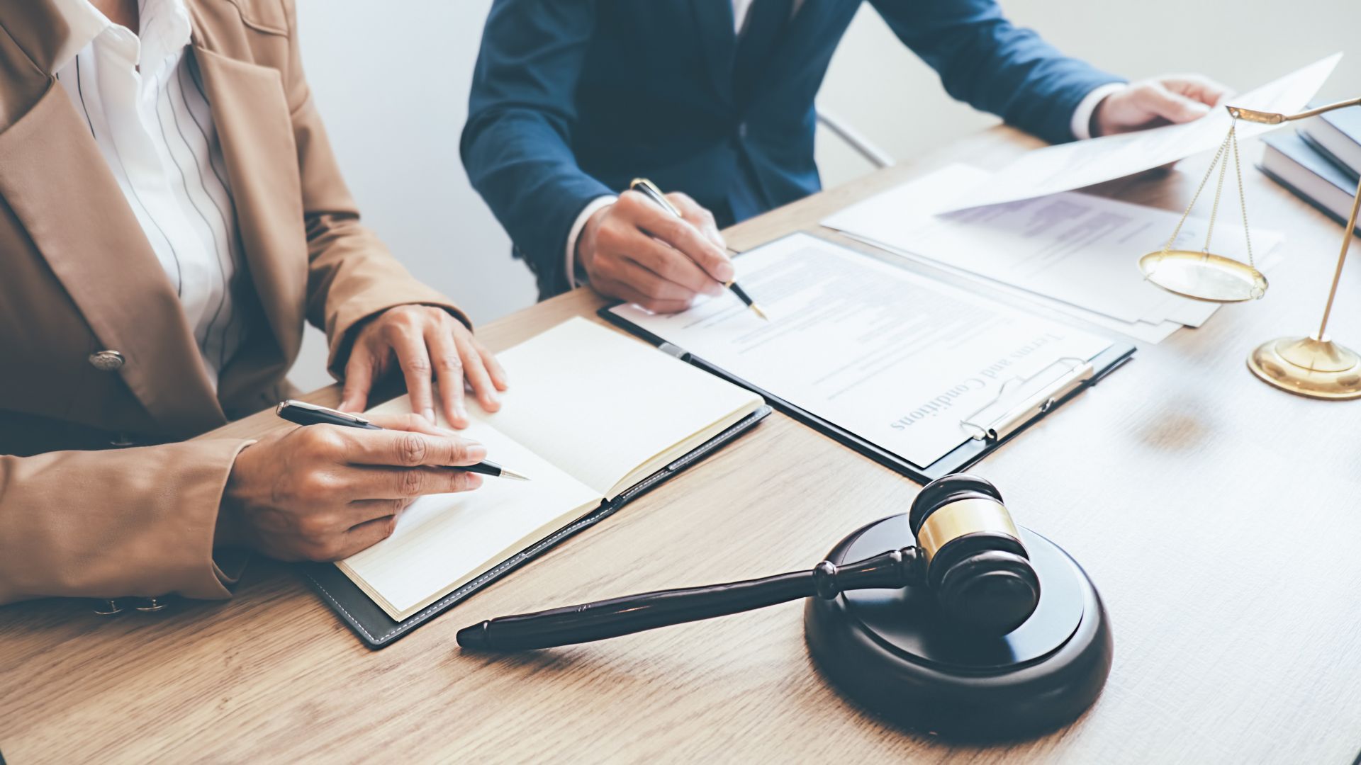 A man and a woman are sitting at a table with papers and a judge 's gavel.