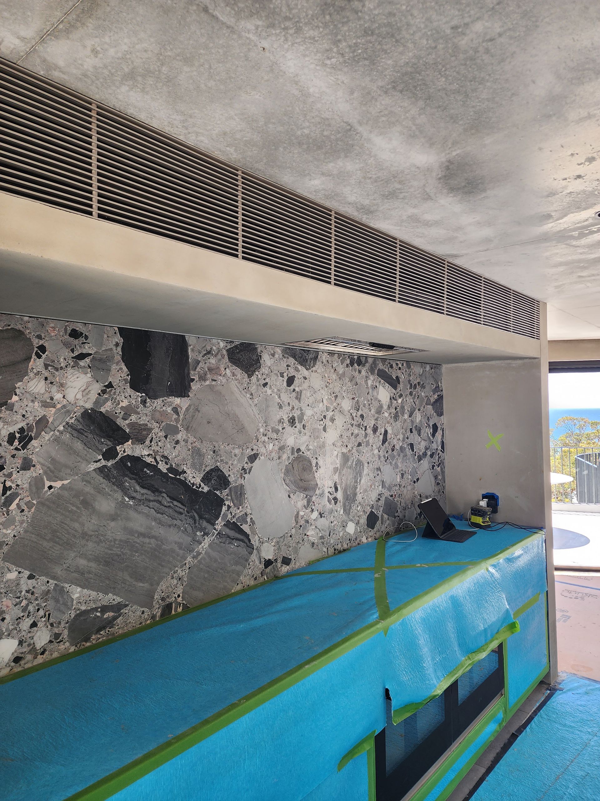 A room with a stone wall and a blue tarp on the floor — Coastline Air In Forresters Beach, NSW