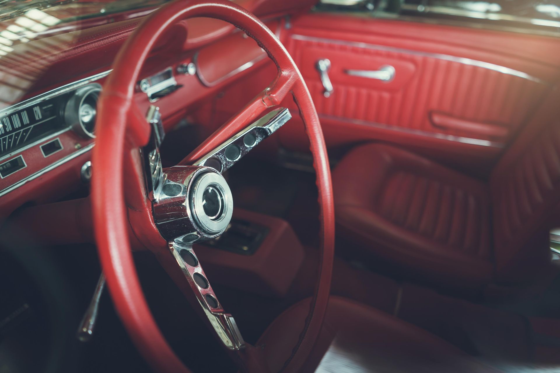 Red interior of a classic car, including steering wheel, dashboard, and seats.
